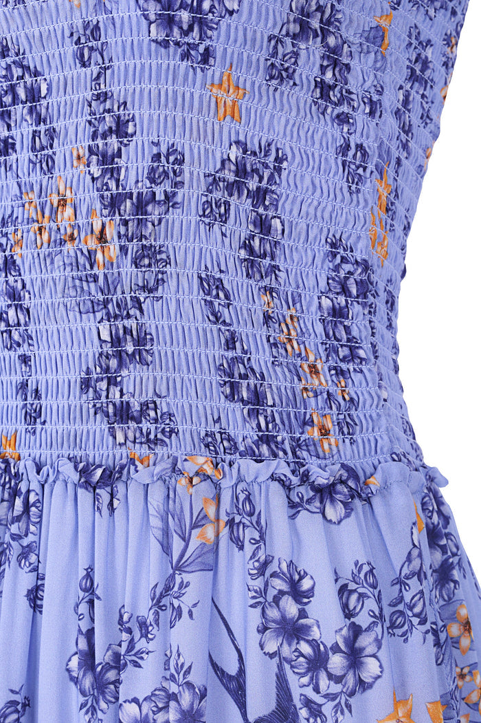 Periwinkle mini dress with smocked bodice, pattern detail print skirt, and scattered orange star embroidery details