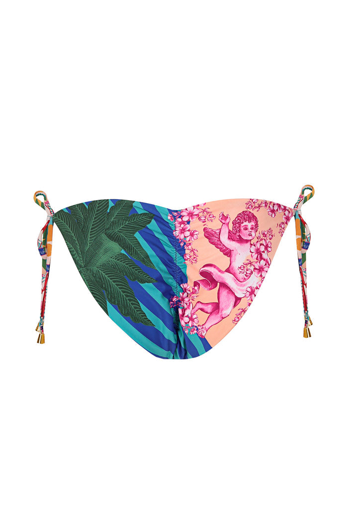 Reversible bikini bottom with side ties, one side showing green palm frond print with blue diagonal stripes, reverse side in peach with pink cherub a…