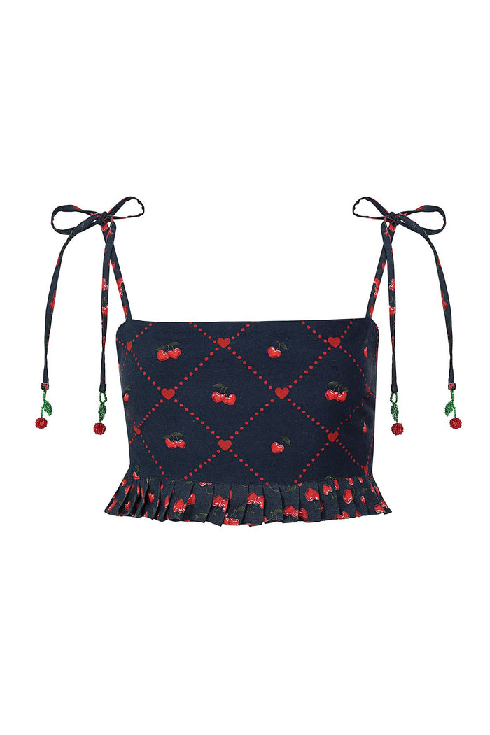 Navy crop top with red cherry print in diamond lattice pattern, ruffled hem, and adjustable shoulder ties with beaded cherry charms