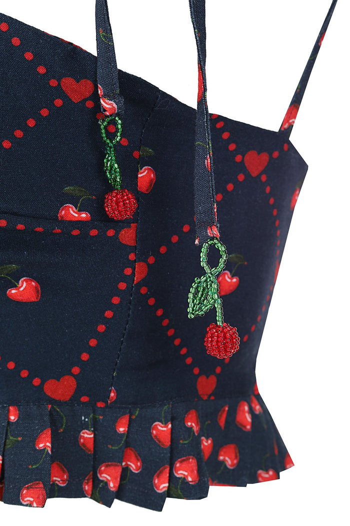 Navy crop top with red cherry and heart print, featuring beaded cherry appliqués on adjustable straps and ruffle hem