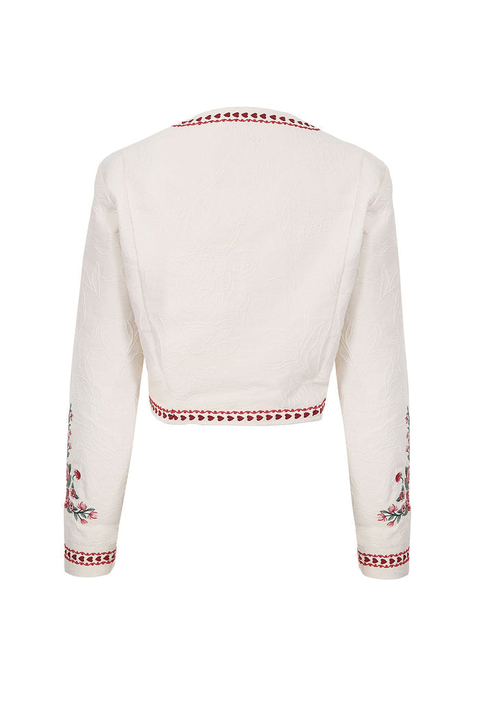 White cropped jacket with textured fabric, red heart trim along neckline, hem and cuffs, and floral embroidery on sleeves
