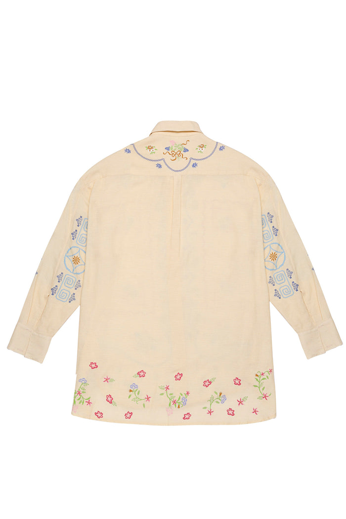 Beige linen shirt with colorful embroidered details featuring small flowers along the hem, geometric patterns on the sleeves, and chain-like stitchin…