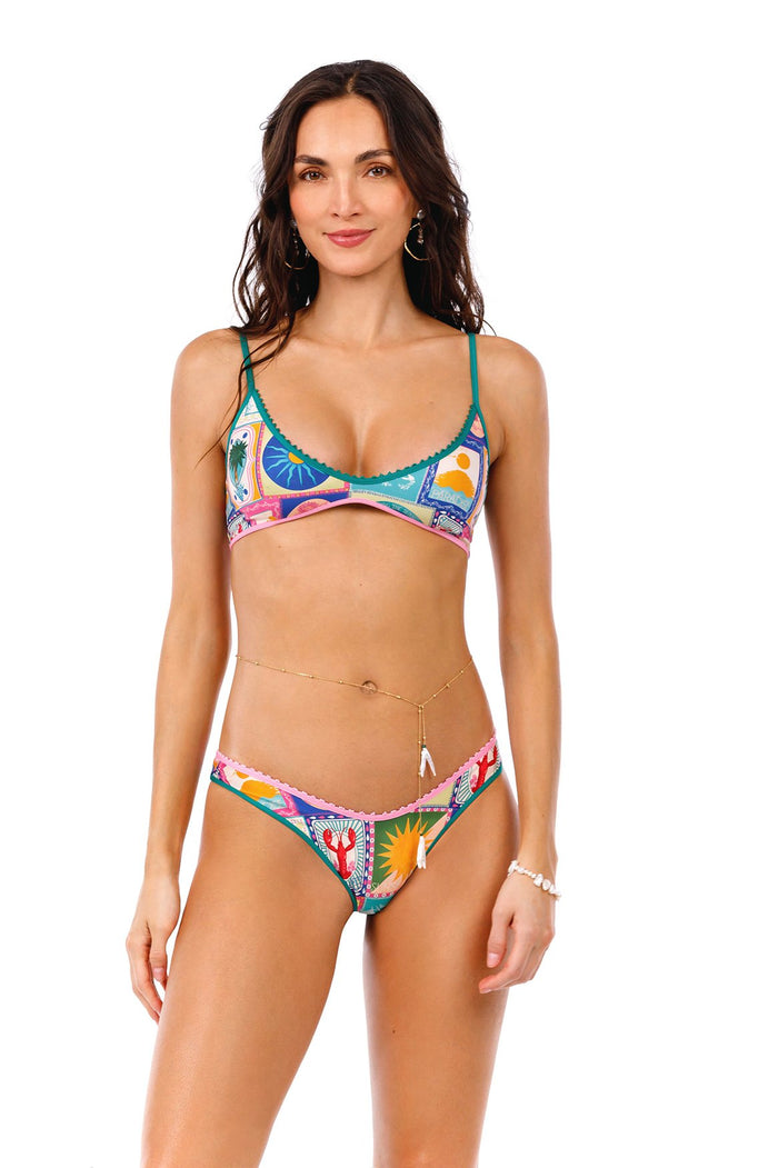 Avy bikini bottom with pink scalloped trim and multicolored geometric print featuring suns, palm trees, and arched panels