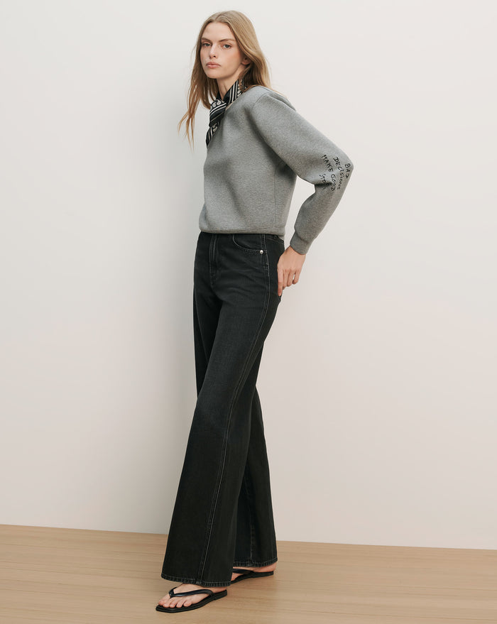 Veronica Beard Gray long-sleeve sweater with a high ruffled neck and black wide-leg jeans.