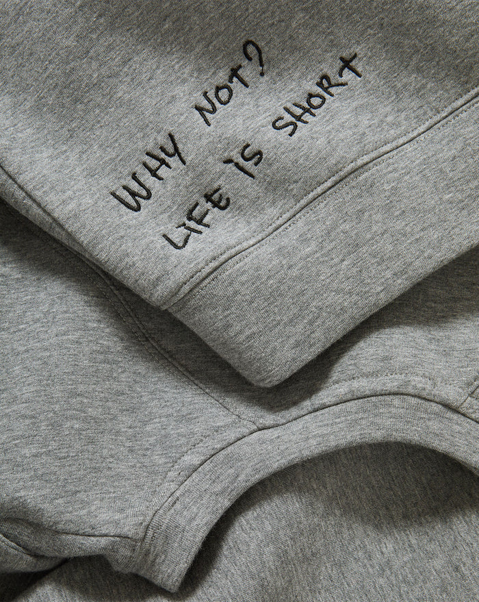 Veronica Beard Gray crewneck sweatshirt with raglan sleeves and dark wash wide-leg jeans with a raw hem.