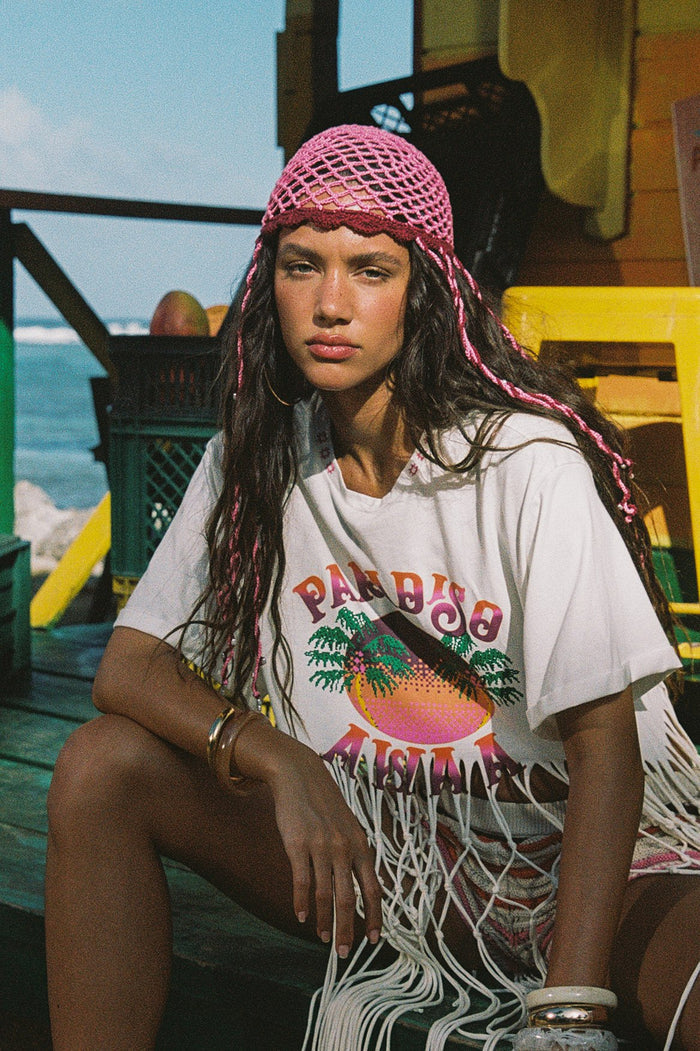 Pink crochet hat with open-weave mesh structure and long braided ties with bead accents