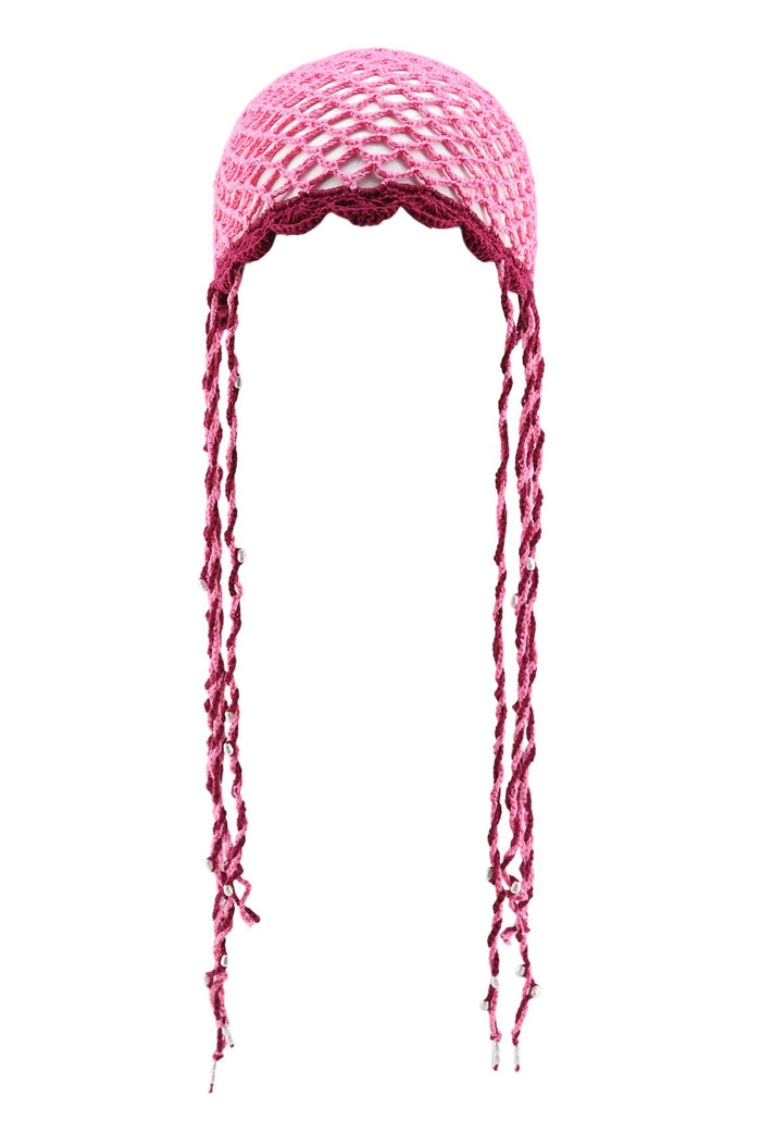 Pink handwoven crochet hat with open lattice structure, scalloped edge, and long braided ties with bead accents