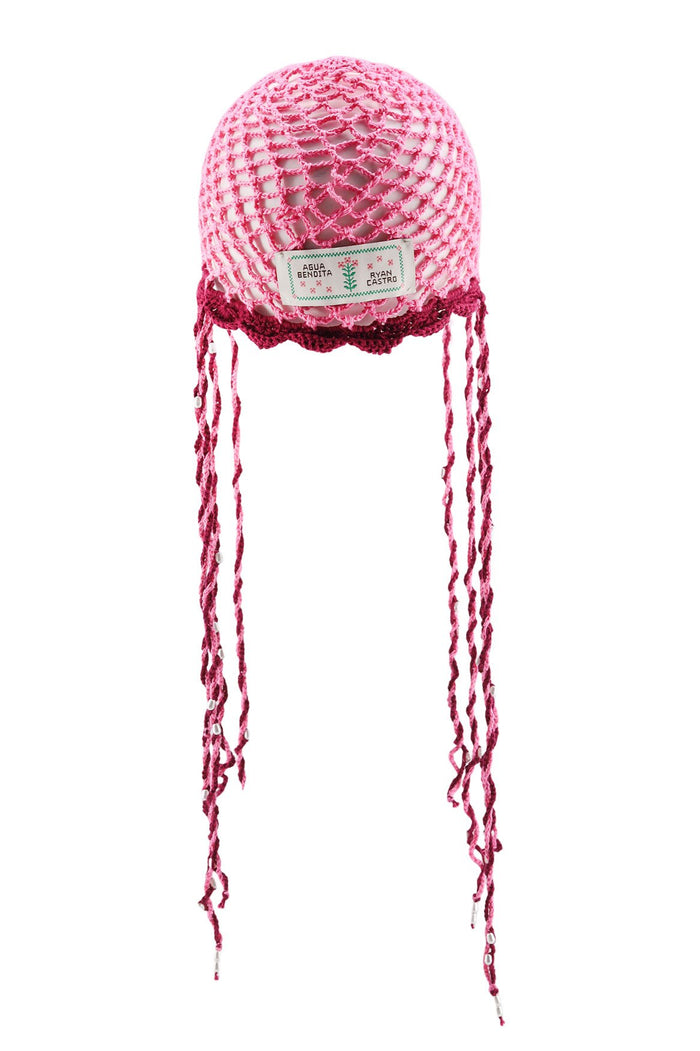 Pink crochet hat with open mesh structure, contrast burgundy trim, and long braided ties with bead details