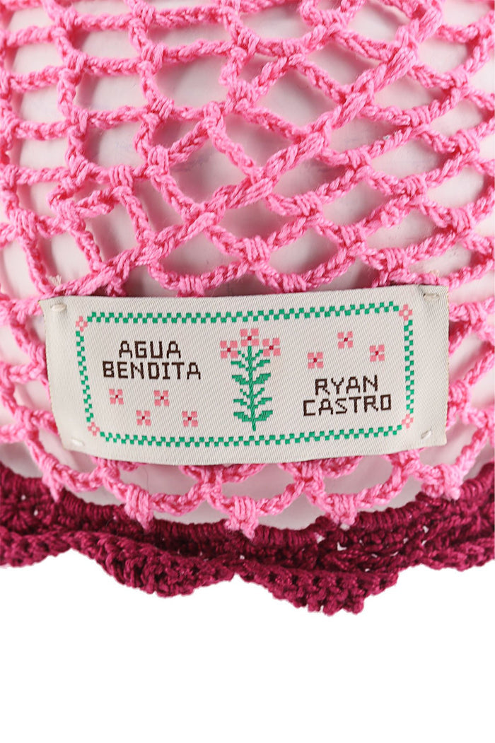 Pink crochet bucket hat with handwoven open-weave pattern and burgundy scalloped trim along the brim