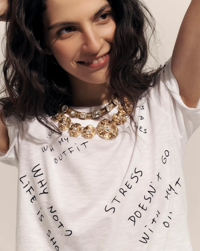 Veronica Beard White short-sleeve t-shirt with black text graphics on the back, paired with dark wash flare jeans.