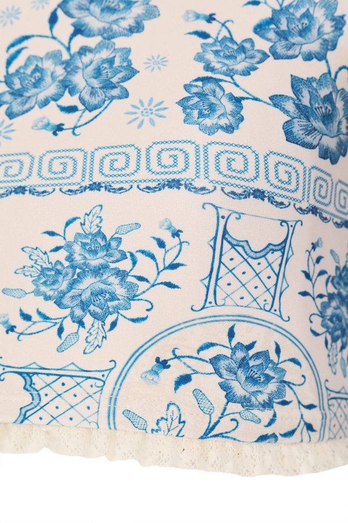 White rashguard set with blue chinoiserie print featuring pattern detail blooms, decorative vases, Greek key border trim, and scalloped lace hemline