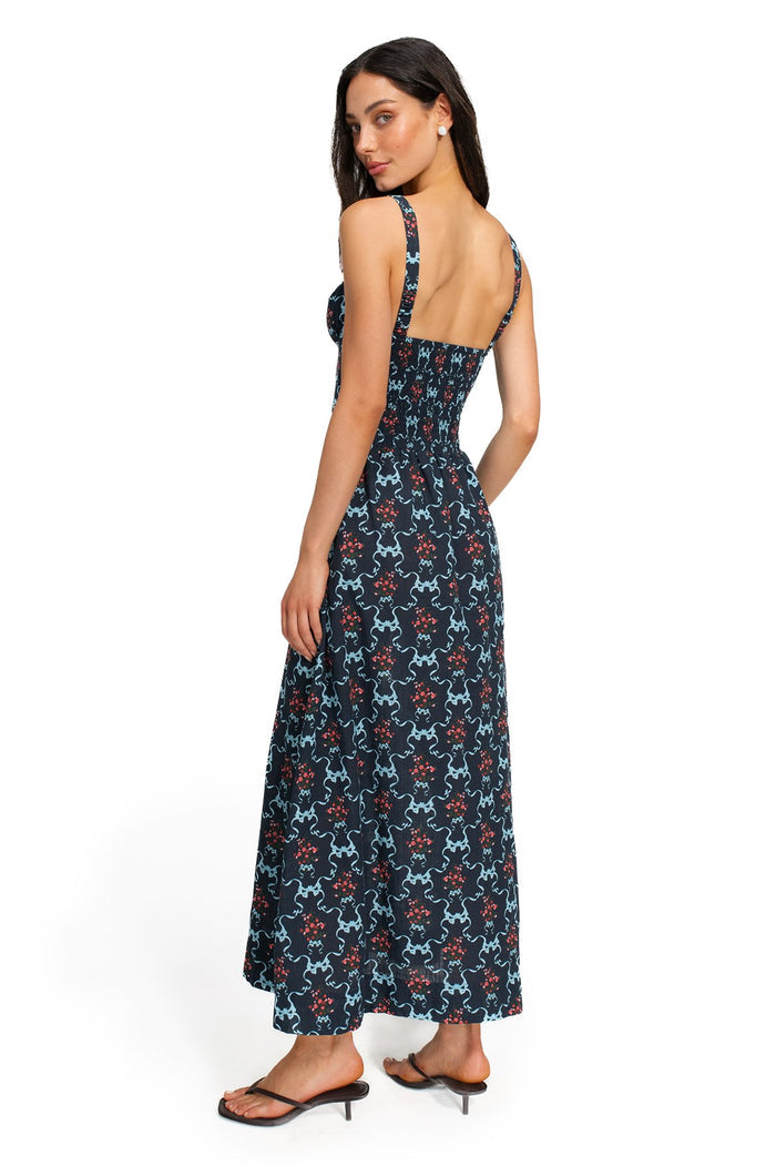 Navy smocked-back maxi dress with blue curved lines and coral dot clusters print, back view