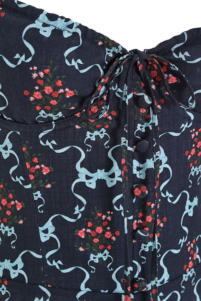 Navy dress with light blue ribbon print and red pattern detail clusters, featuring front button closure and gathered tie detail at neckline