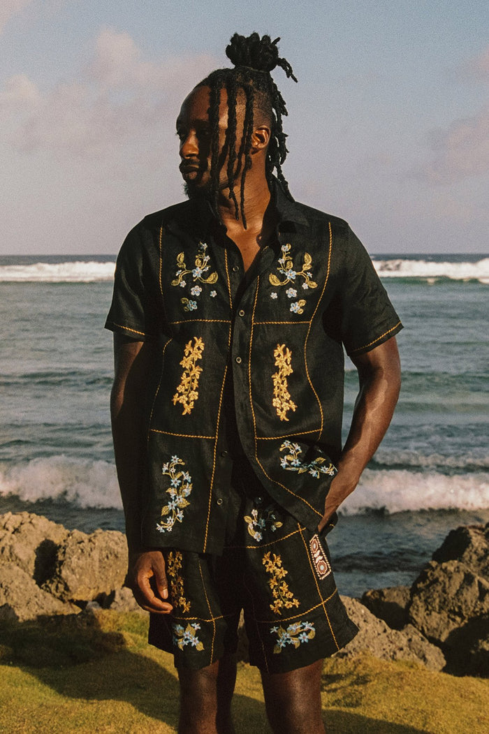 Black men's shorts with embroidered floral details in gold, white and blue arranged in a grid pattern with contrast stitching
