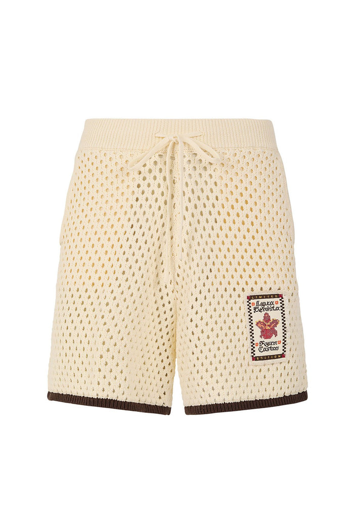 Cream crochet-knit shorts with drawstring waist, brown contrast hem trim, and branded patch detail on front