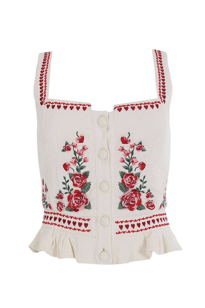 White crop top with red floral embroidery, heart trim details, front button closures, and ruffle hem
