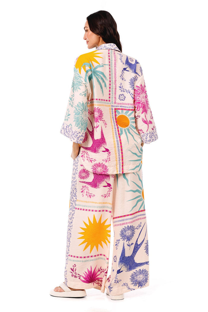 Chrissy shirt in cream with colorful placement print featuring yellow suns, teal palm fronds, pink and purple pattern detail elements, and striped ge…