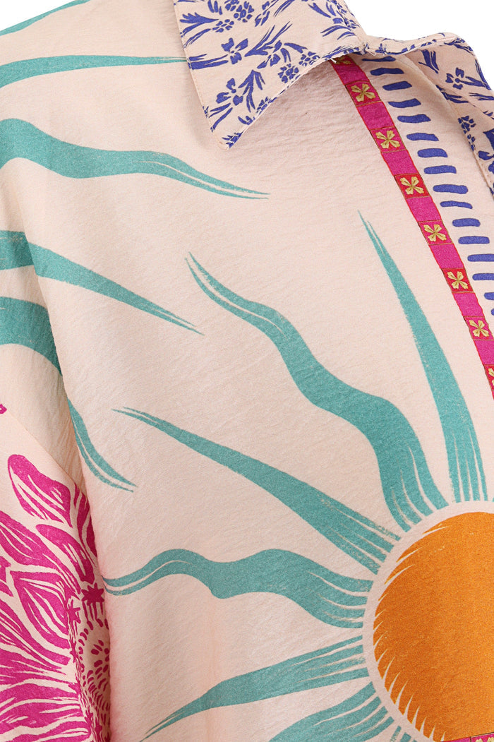 Chrissy shirt in cream with turquoise wave pattern, pink pattern detail print, orange sun detail, and blue botanical print collar with pink embroider…