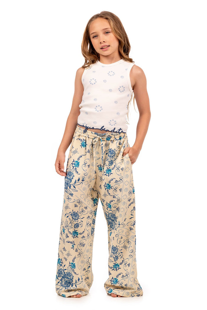 Wide-leg pants in cream with blue pattern detail print and decorative scrolls, paired with a white sleeveless top with embroidered starburst details