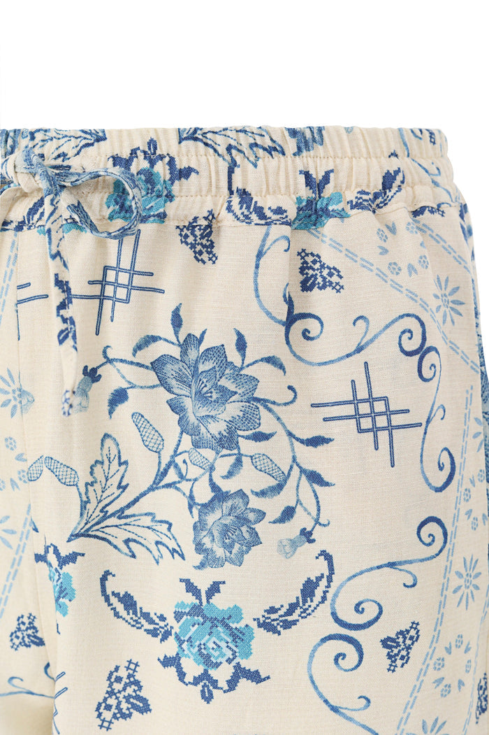 Cream pants with blue pattern detail print featuring scrollwork and lattice details, elastic waistband with drawstring