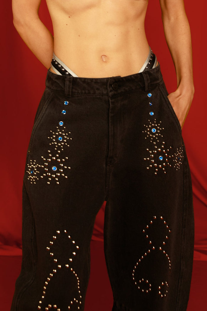 Black denim pants with rhinestone and silver stud embellishments in starburst patterns