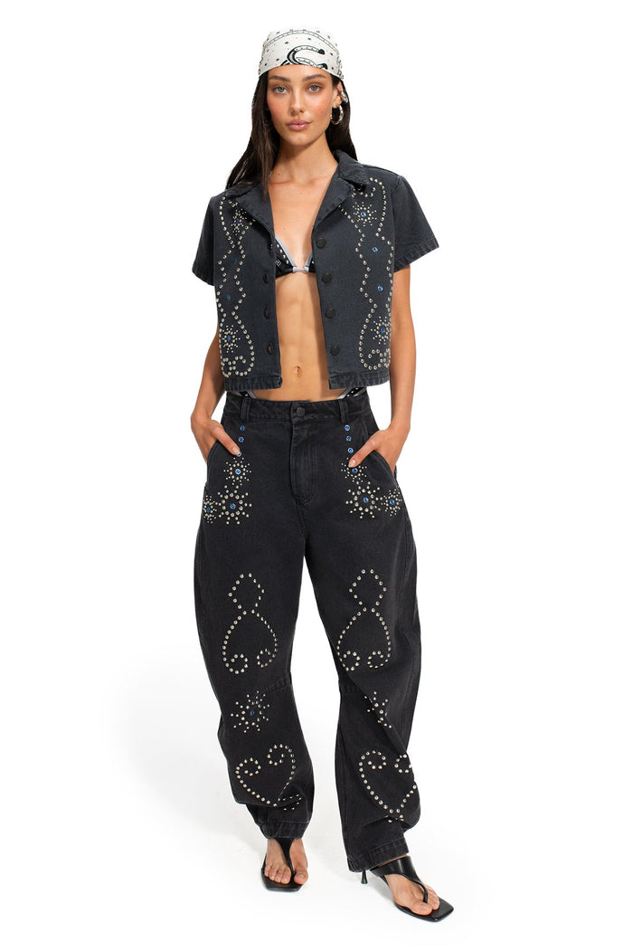 Black denim pants with rhinestone and silver stud embellishments forming geometric hearts and diamond patterns on pockets and legs