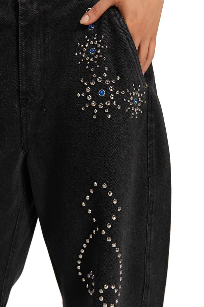 Black denim pants with rhinestone and silver stud embellishments forming geometric patterns along the leg and pocket