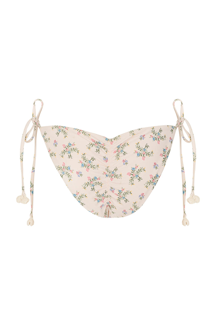 Fawna bikini bottom in blush with scattered pattern detail print, featuring side ties with handmade crochet pom-pom details