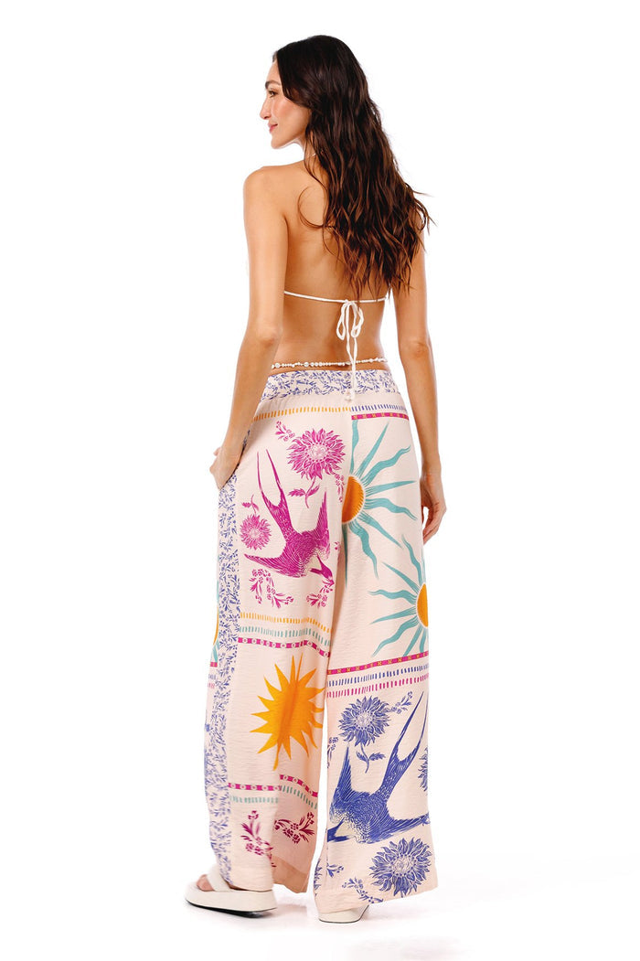 Wide-leg pants in cream with colorful placement print featuring swallows, sunbursts, botanical florals and geometric borders