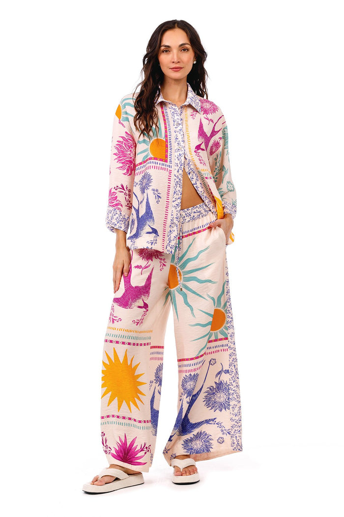 Janis wide-leg pants in cream with vibrant placement print featuring suns, botanical silhouettes, and geometric trim details