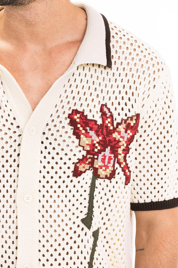 Cream crochet-knit shirt with open mesh pattern, embroidered red flower appliqué, and contrasting brown trim on collar and sleeves
