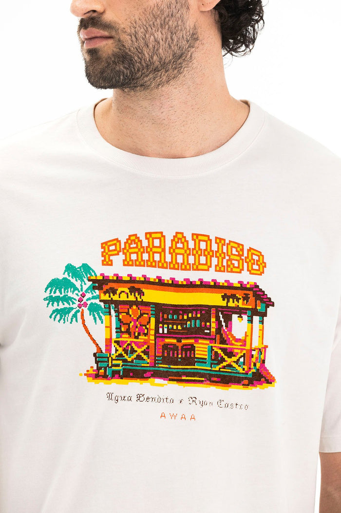 White t-shirt with embroidered pixel-art design featuring colorful tropical beach hut, palm tree, and Paradise text