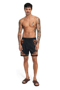 Black swim trunks with coral and cream pattern detail embroidery along sides and scalloped hem trim