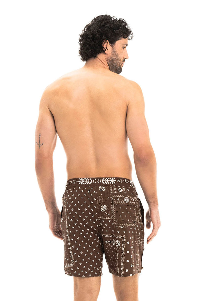 Brown swim trunks with white geometric bandana print featuring diamonds, florals, and cross details