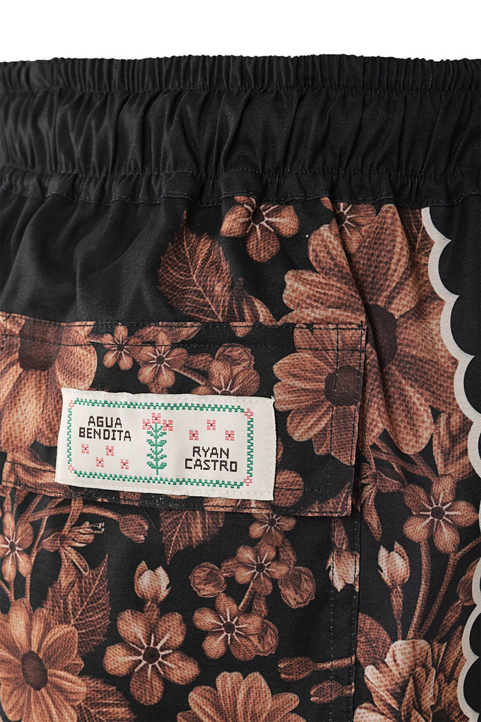 Black swim trunks with brown pattern detail print, elastic waistband, and side scalloped trim detail
