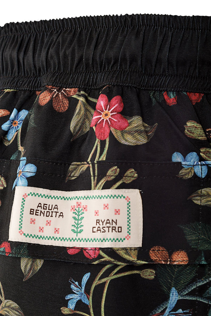 Black swim trunks with allover floral print featuring pink, blue, and coral blooms with green leaves