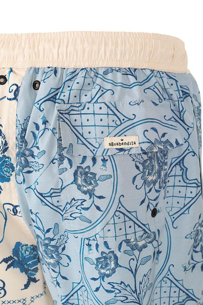 Light blue swim trunks with ornamental blue grid pattern and pattern detail details, elastic waistband in cream, back pocket with fabric label