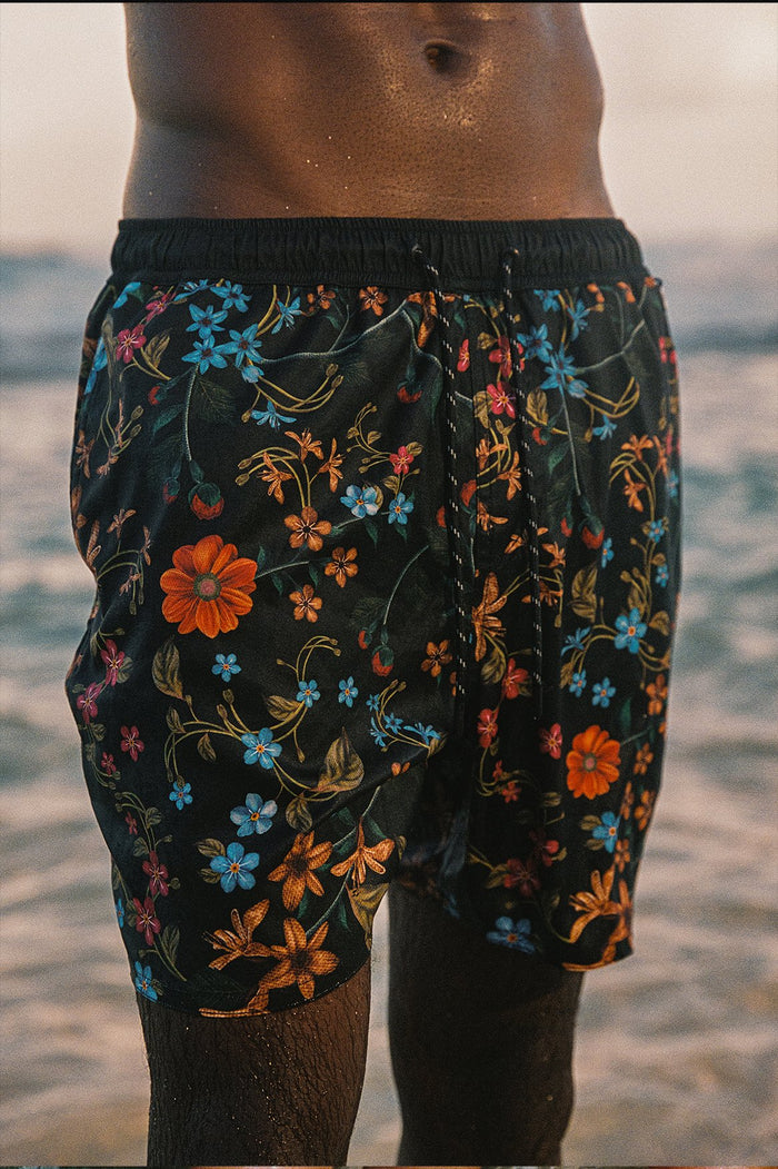 Black swim trunks with multicolor floral embroidery and elastic waistband