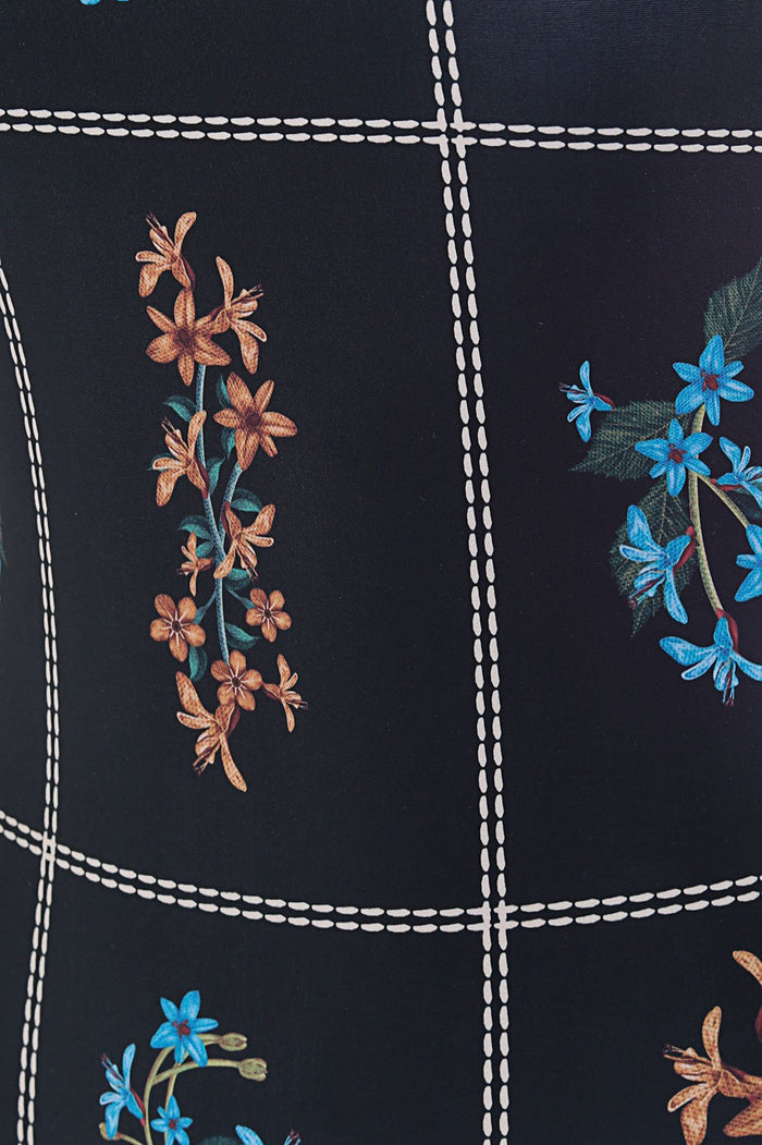 Black swimsuit with white contrast stitching grid pattern and embroidered orange and blue pattern detail branches