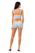 Light blue smocked shorts with ruched tiers, lace trim straps, and delicate pattern detail print, back view