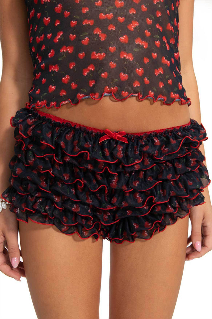 Black mesh shorts with red cherry print, tiered ruffles, red piped trim and bow detail at waistband