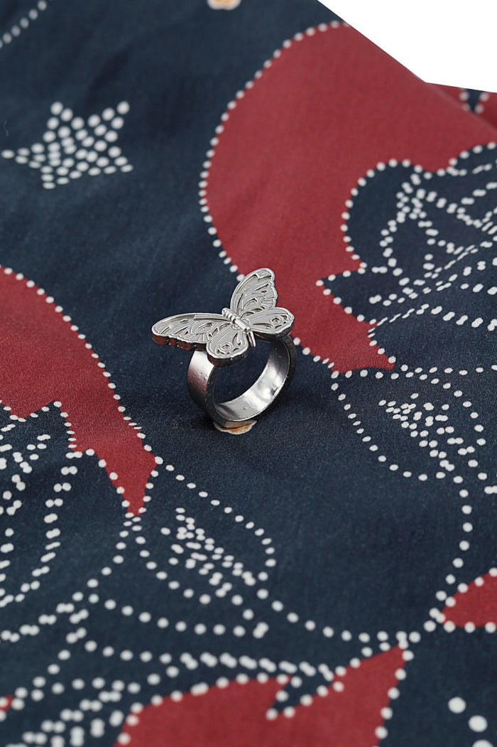 Silver butterfly ring on navy and coral scarf with white dotted geometric print