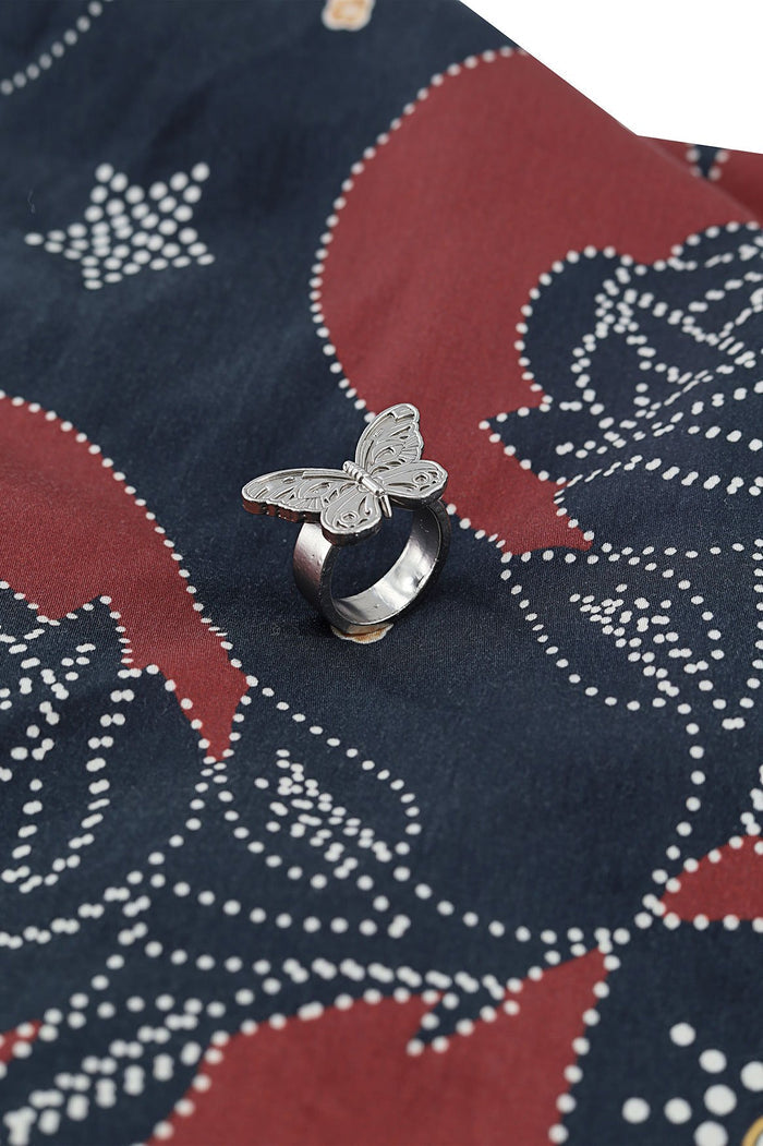 Silver butterfly ring on navy and terracotta scarf with white dotted geometric print