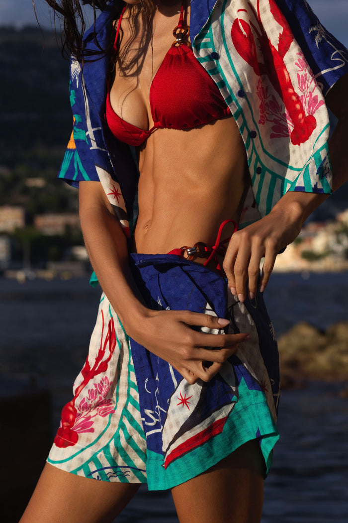 Red bikini top and blue Lia shorts with multicolor geometric print featuring pink florals, turquoise and red graphic elements, paired with matching p…