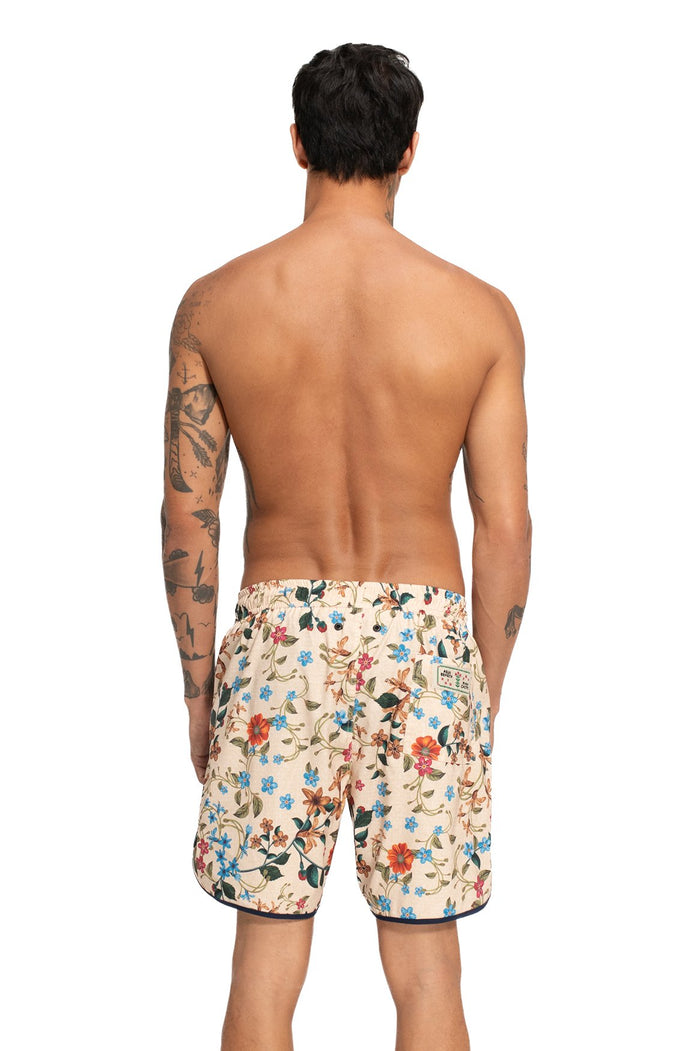 Liam men's swim trunks in cream with multicolor floral print, back view showing elastic waistband and embroidered patch