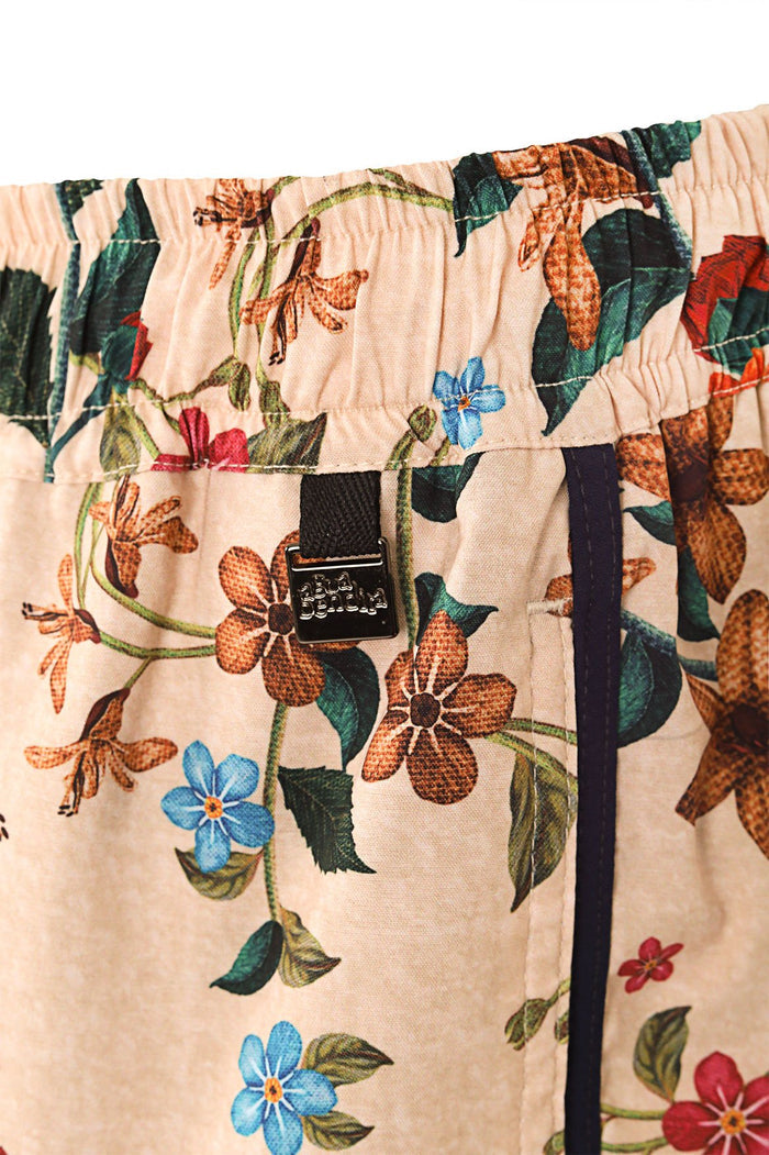 Liam men's trunks in peach with botanical floral print featuring orange, blue, and red blossoms with green leaves, elastic waistband with drawstring…