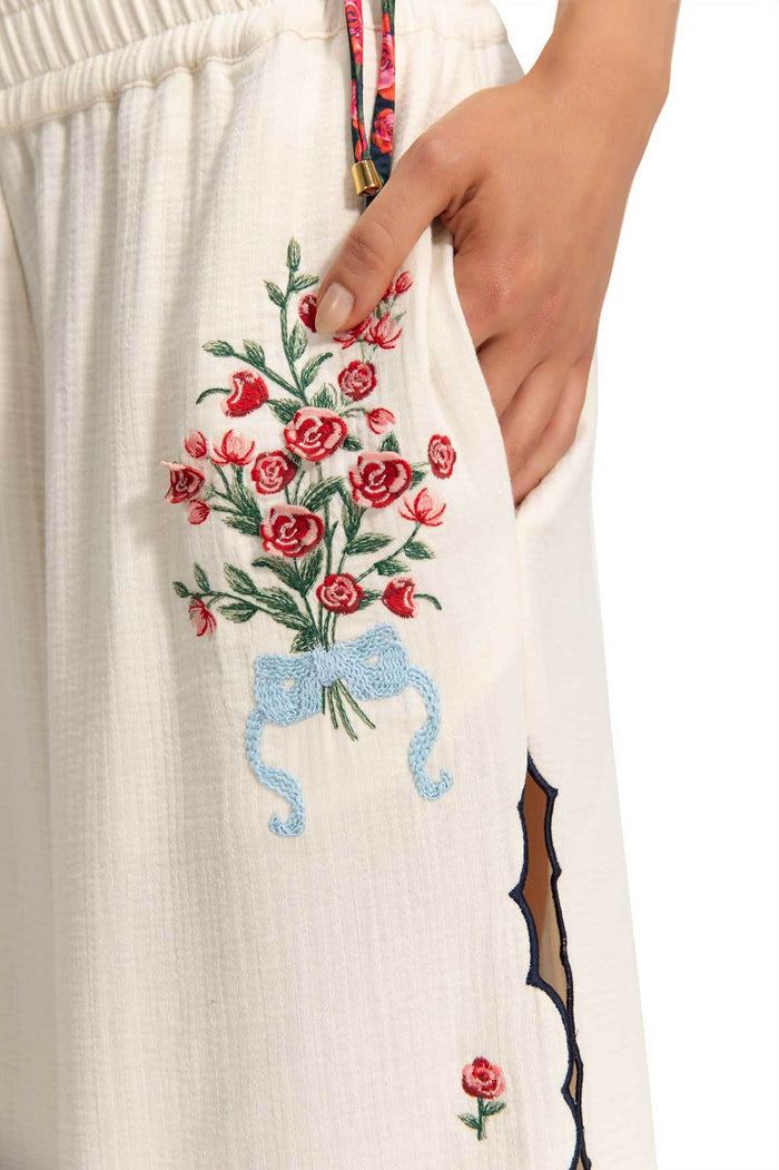 White wide-leg pants with embroidered pattern detail bouquet tied with blue ribbon and laser-cut side details