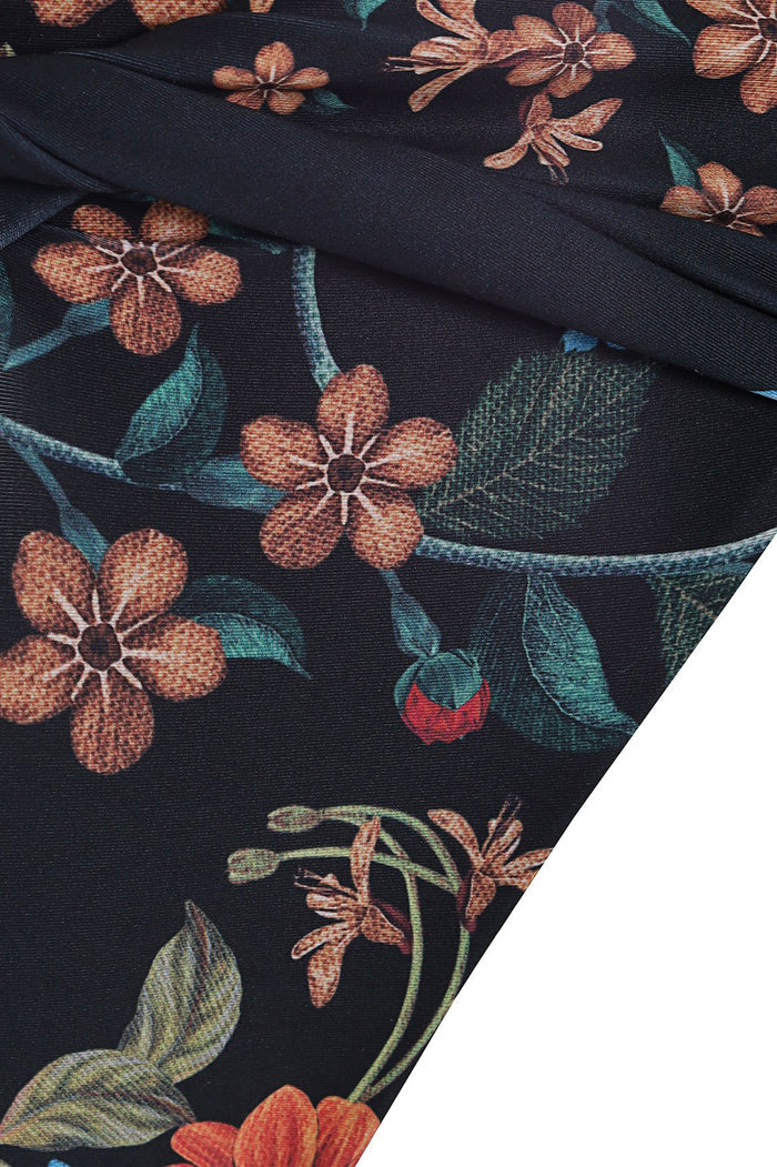 Black high-rise bikini bottom with botanical print featuring coral flowers, teal and green leaves, and dragonfly silhouettes