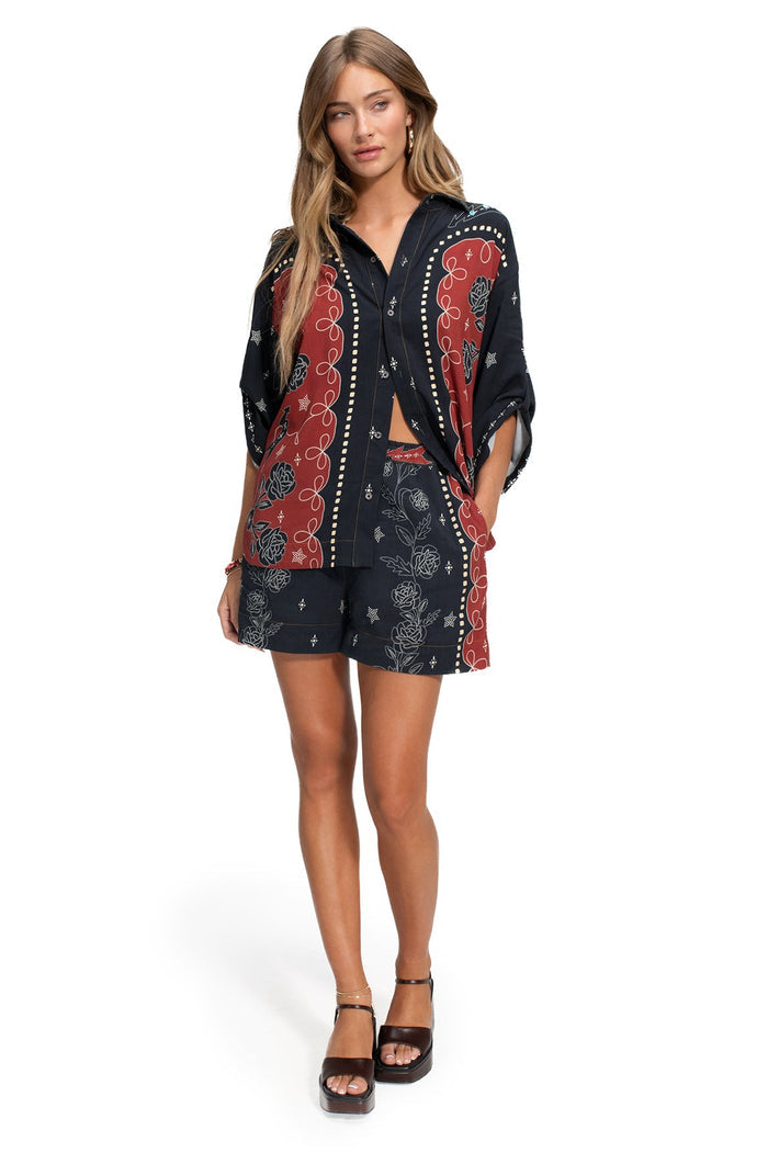Black shorts with terracotta panel borders, white dot trim, and rose outline print