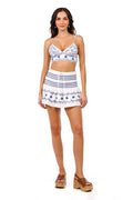 White crop top with blue pattern detail embroidery and matching high-waisted skirt with smocked waistband
